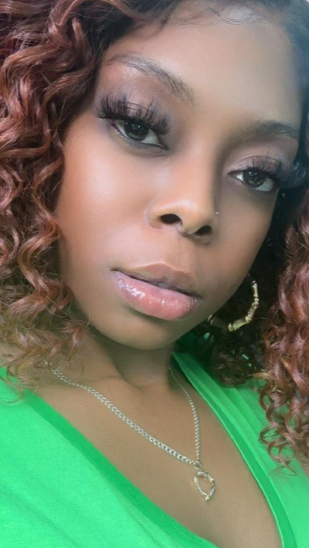 Woman with curly hair wearing a green top against a blurred background